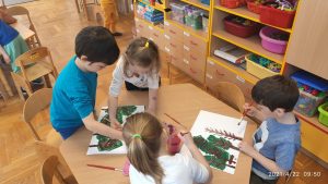 Dzieci malują farbami las.