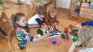 Dzieci malują farbami las.
