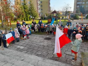 Przedszkolaki ustawione w ogródku przedszkolnym śpiewają hymn Polski