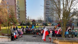 Przedszkolaki ustawione w ogródku przedszkolnym śpiewają hymn Polski